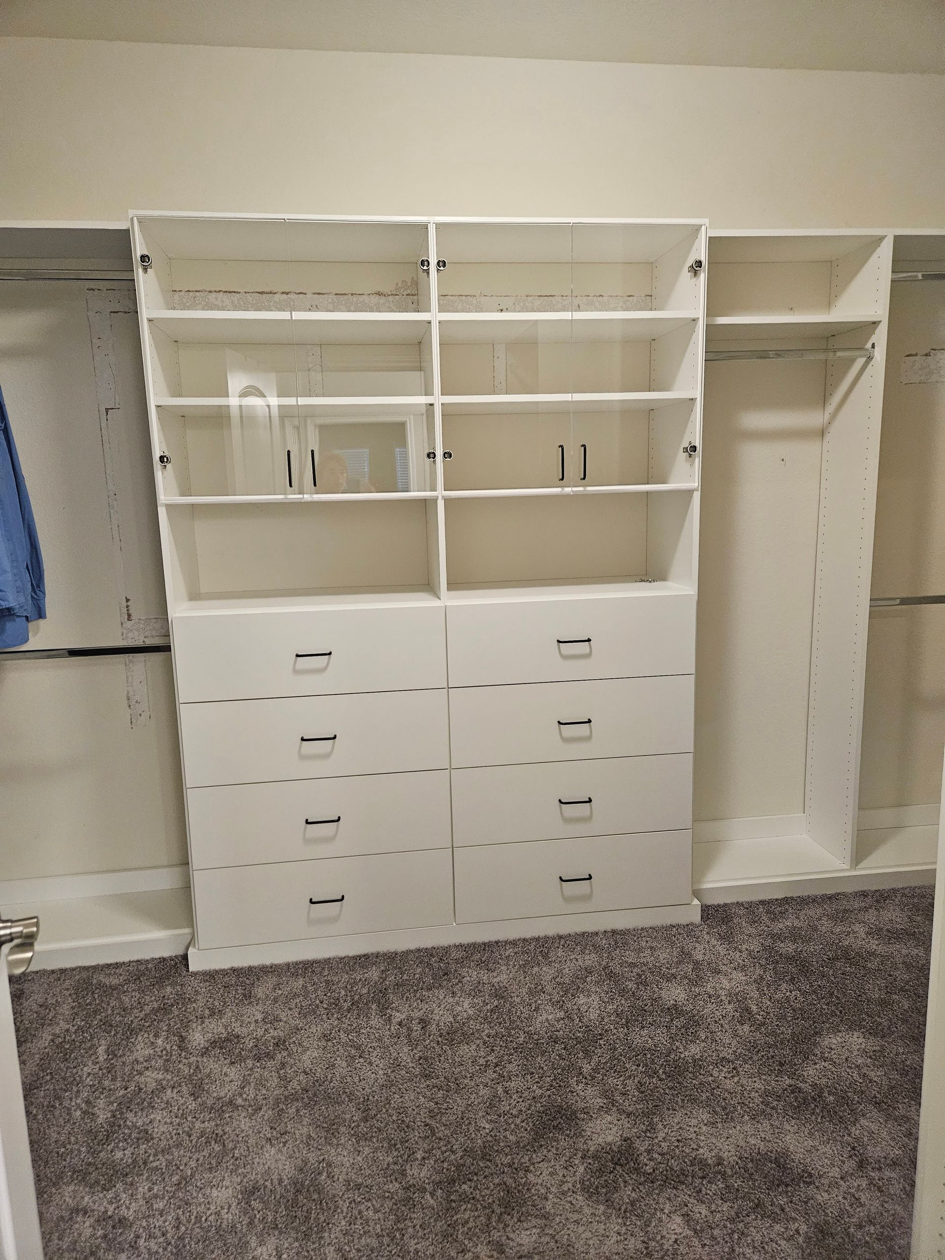 A walk in closet with a lot of shelves and drawers.