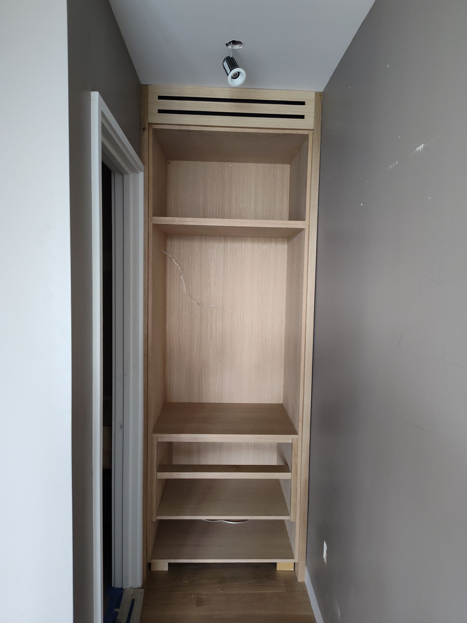 A wooden closet with shelves in a hallway.
