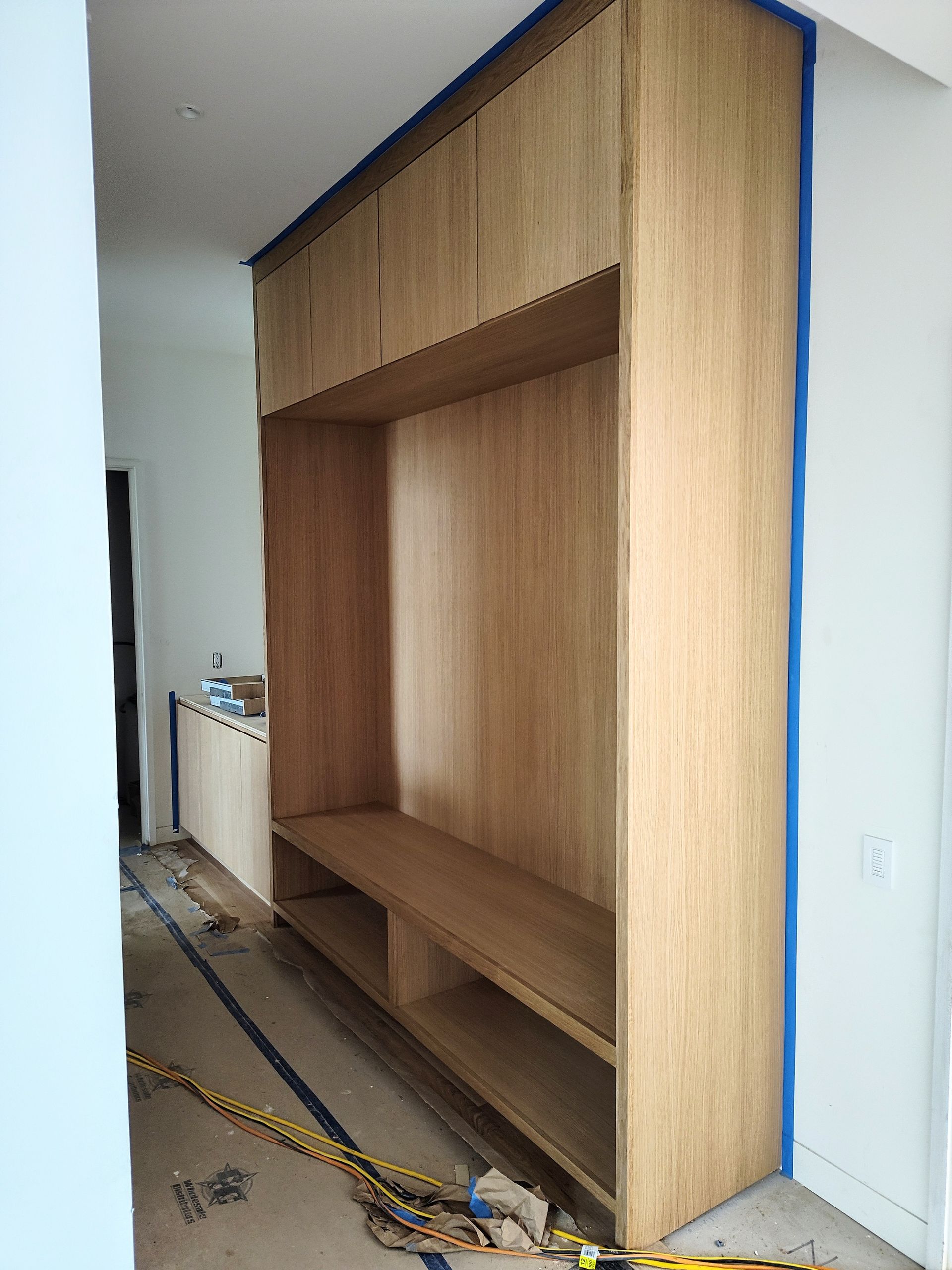 A large wooden cabinet is being built in a room.