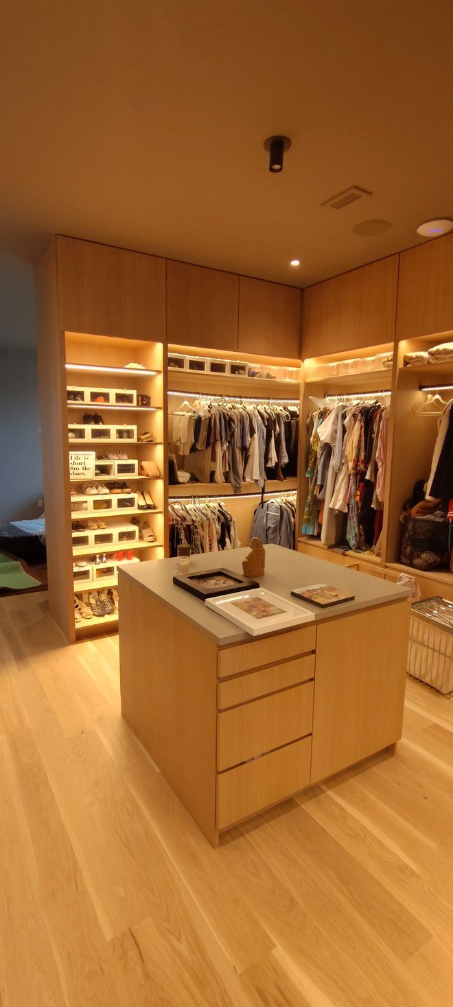 A walk in closet with lots of clothes and a large island in the middle.