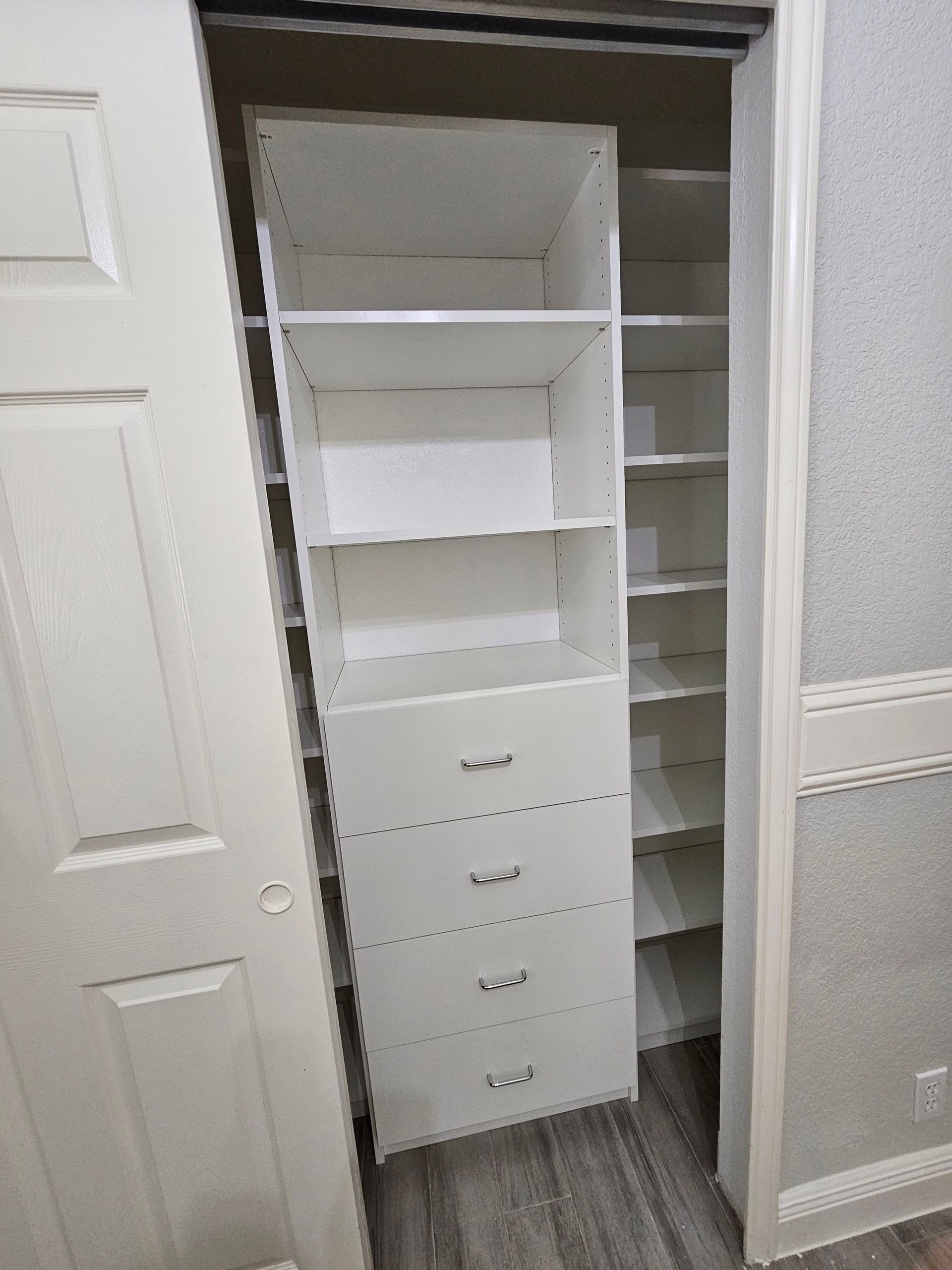A closet with shelves and drawers and a door open.