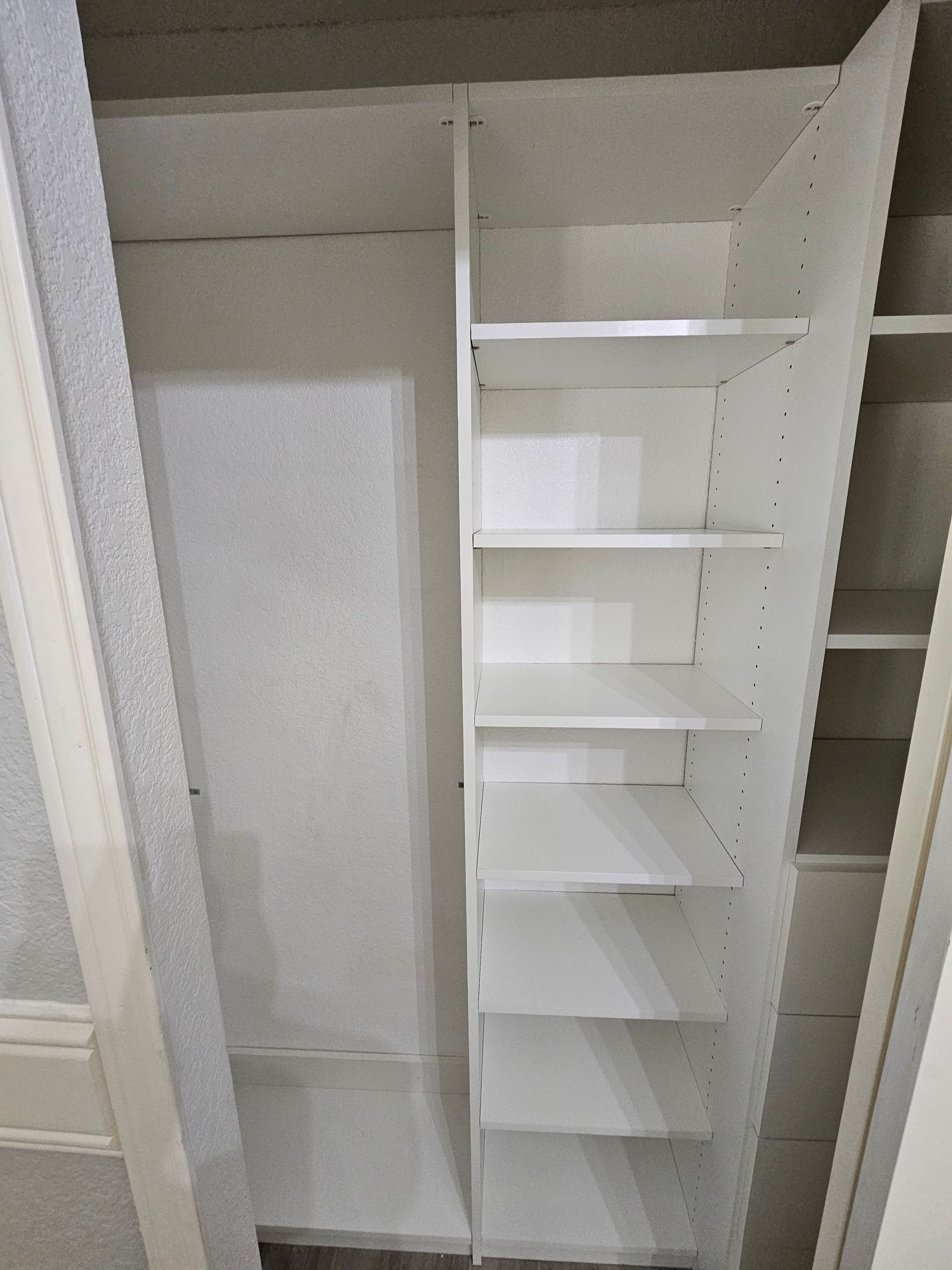 A closet with white shelves and a door.
