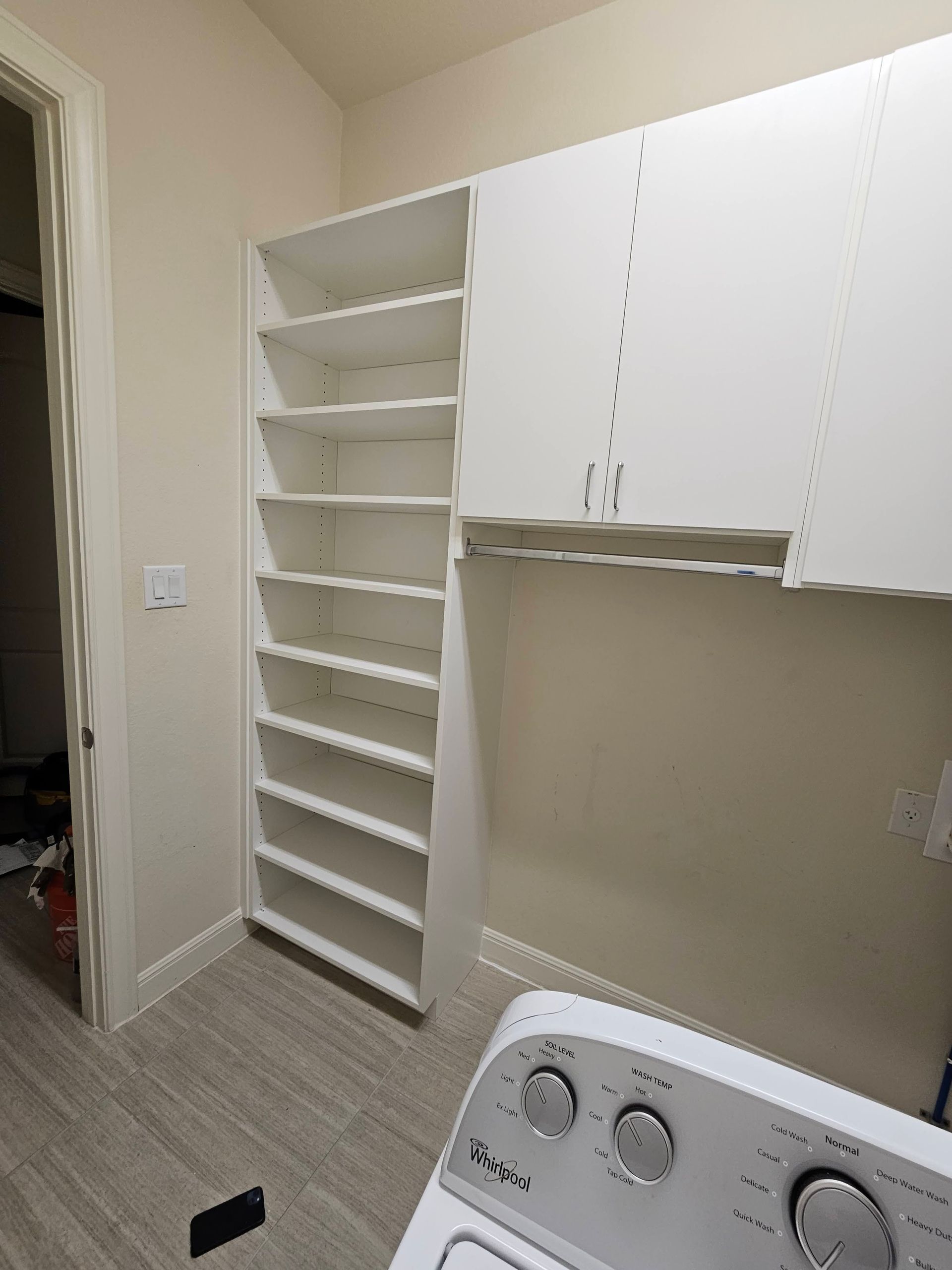 A laundry room with a washer and dryer and shelves.