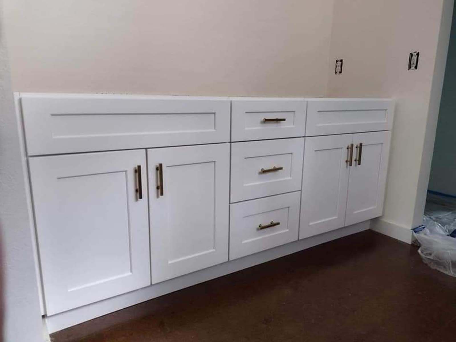 A bathroom vanity with white cabinets and drawers in a room.