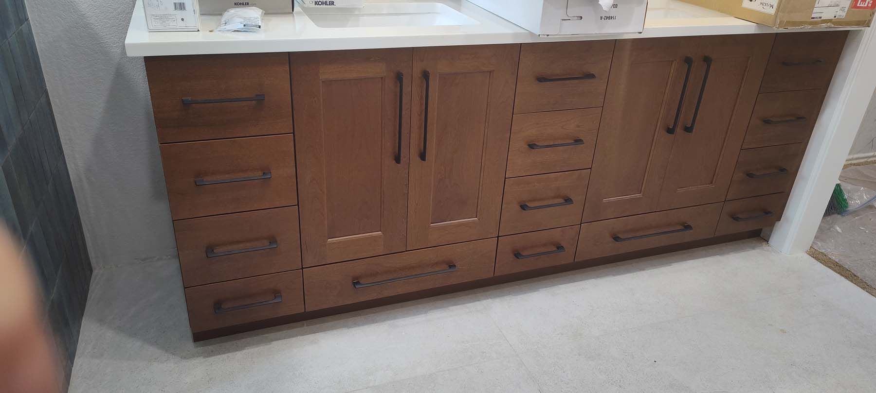A bathroom vanity with wooden cabinets and drawers is being built.