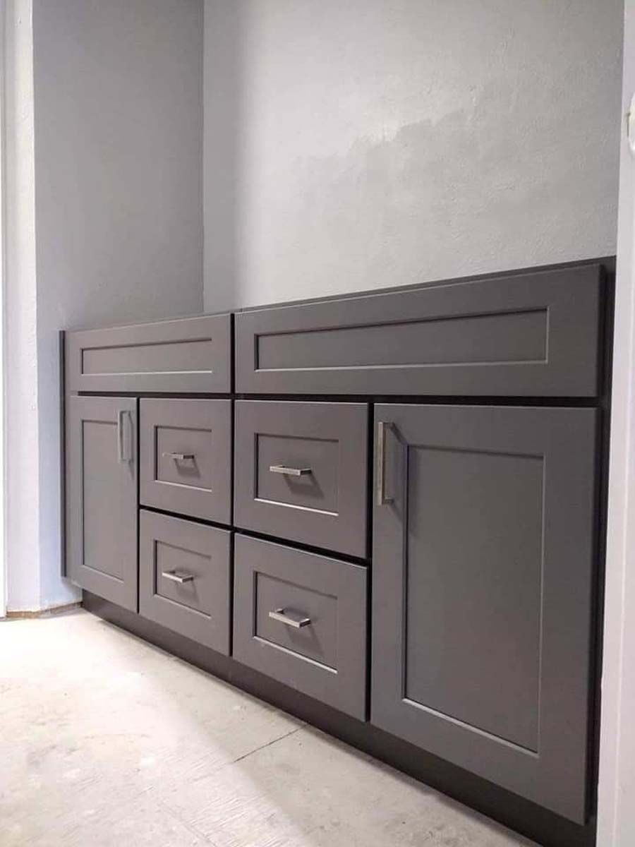 A bathroom vanity with gray cabinets and drawers.