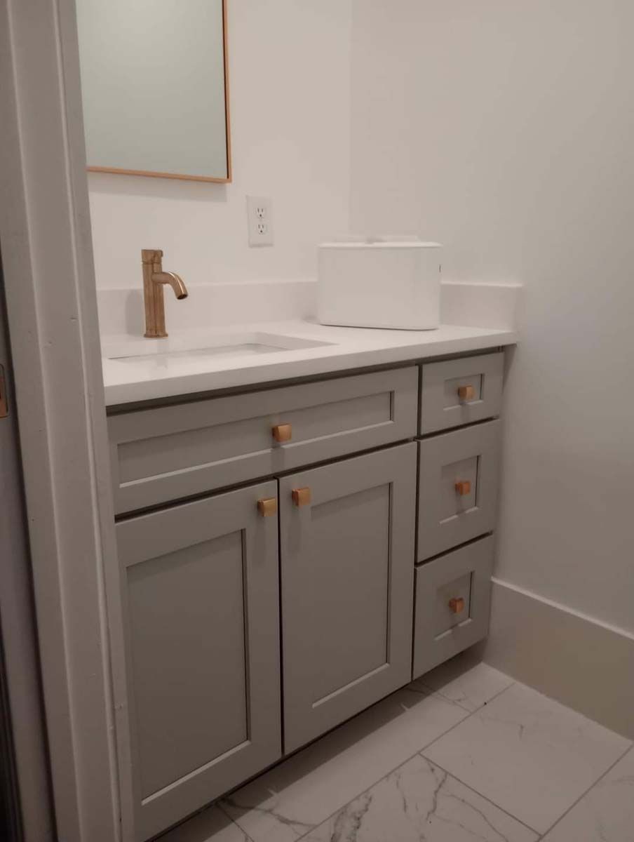 A bathroom with a sink , cabinets , drawers and a mirror.