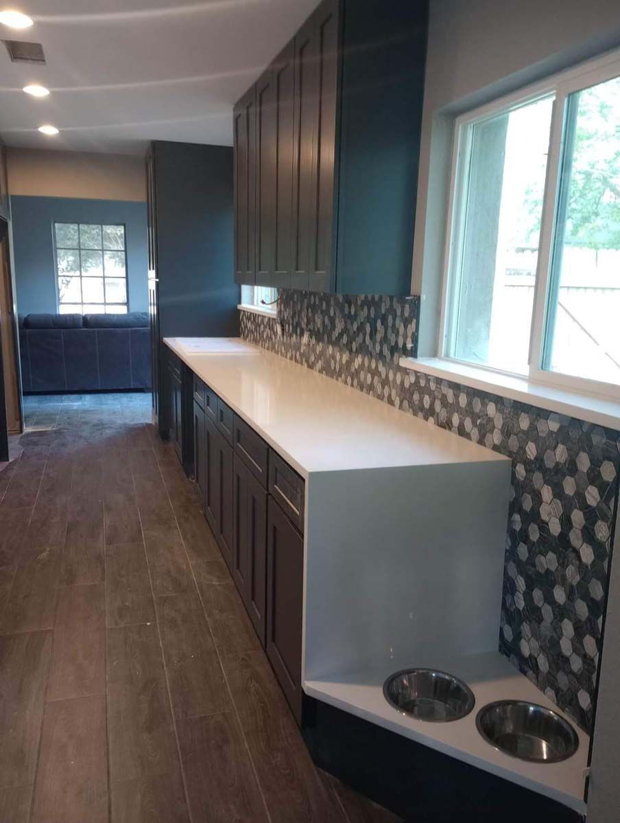 A kitchen with a long counter and two dog bowls