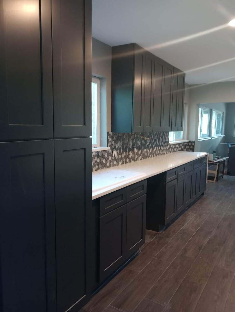 A kitchen with black cabinets and white counter tops.