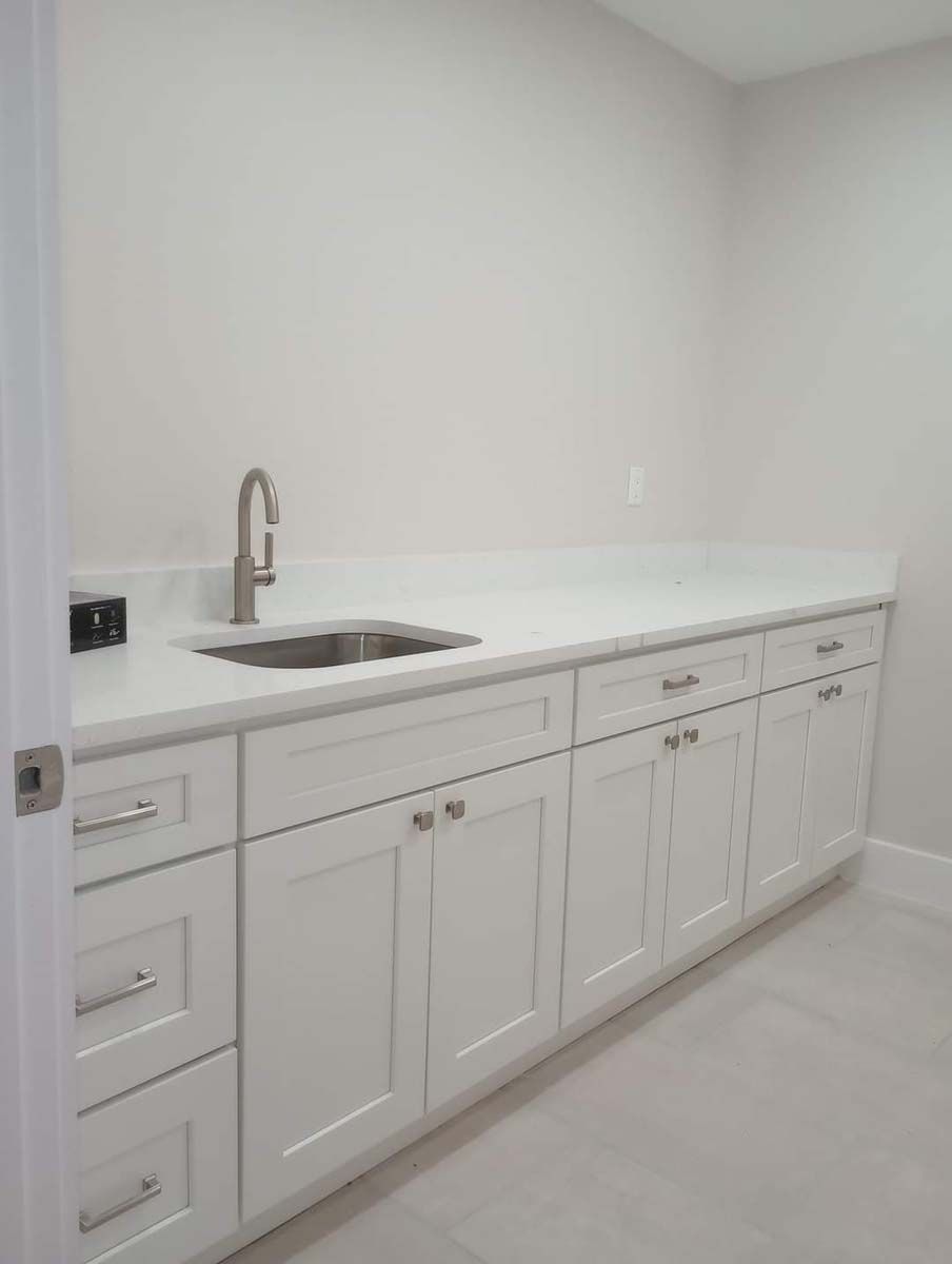 A kitchen with white cabinets and a sink.