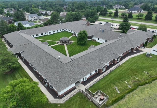 Aerial view of a long, one-story building surrounding a central courtyard with green grass and a gazebo.