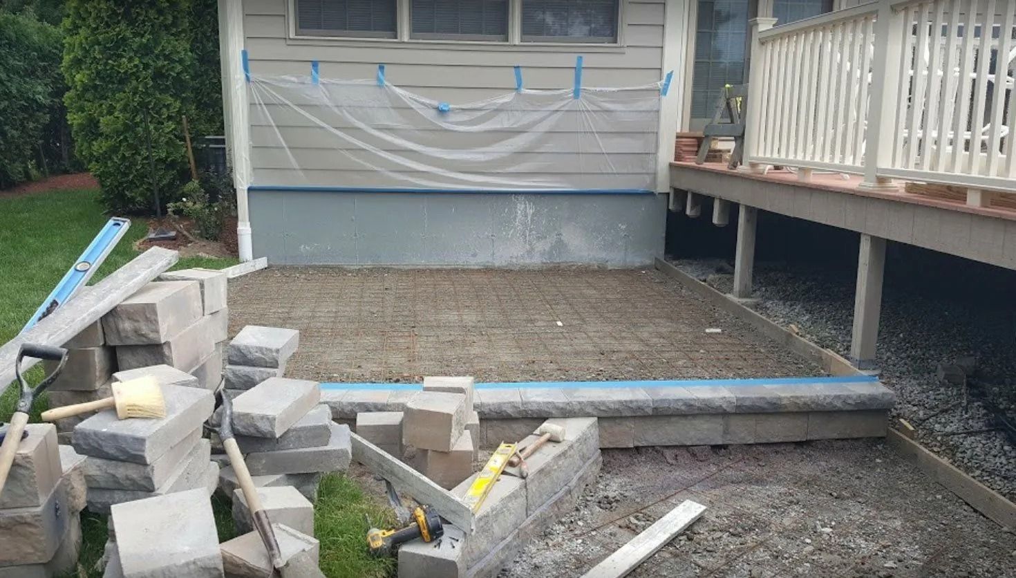 Construction of a patio with stacked gray blocks, gravel, and leveling tools.