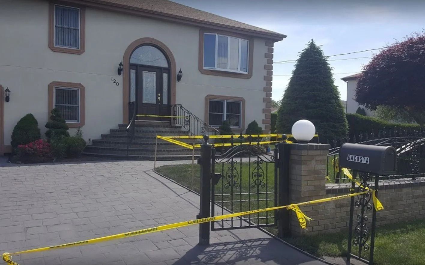 A house exterior with yellow caution tape. A brick driveway leads to the front door.