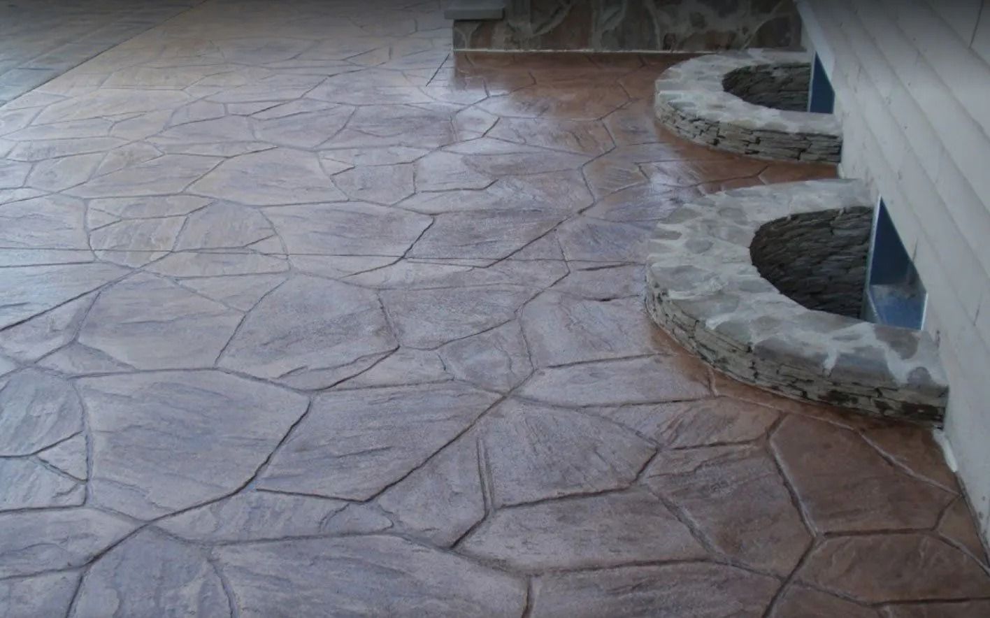 Stone-patterned concrete patio with two built-in planters on the right side. Earth-tone colors.