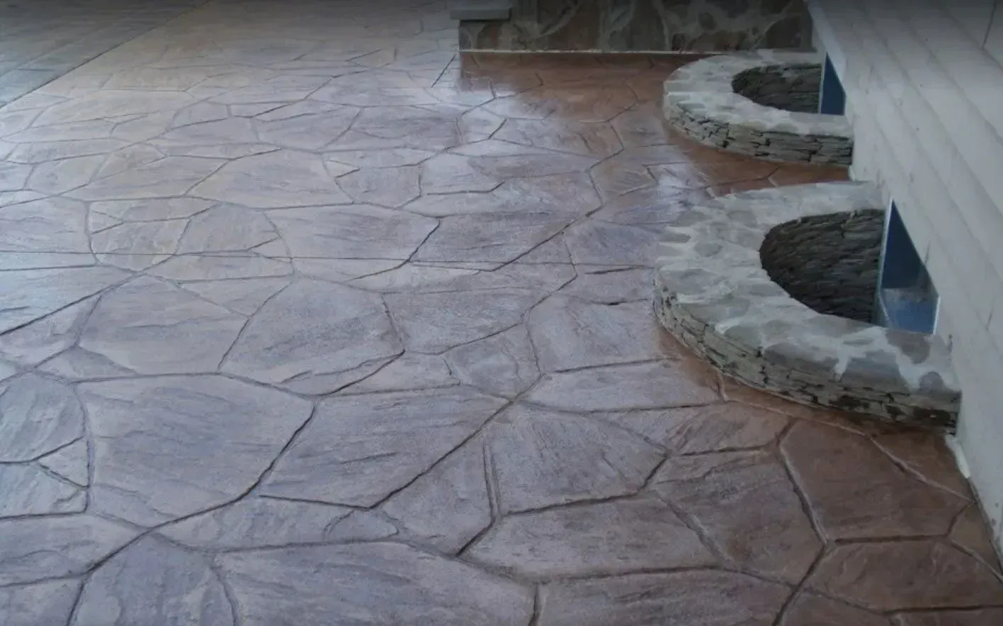 Textured concrete patio with a flagstone pattern in shades of brown and gray.