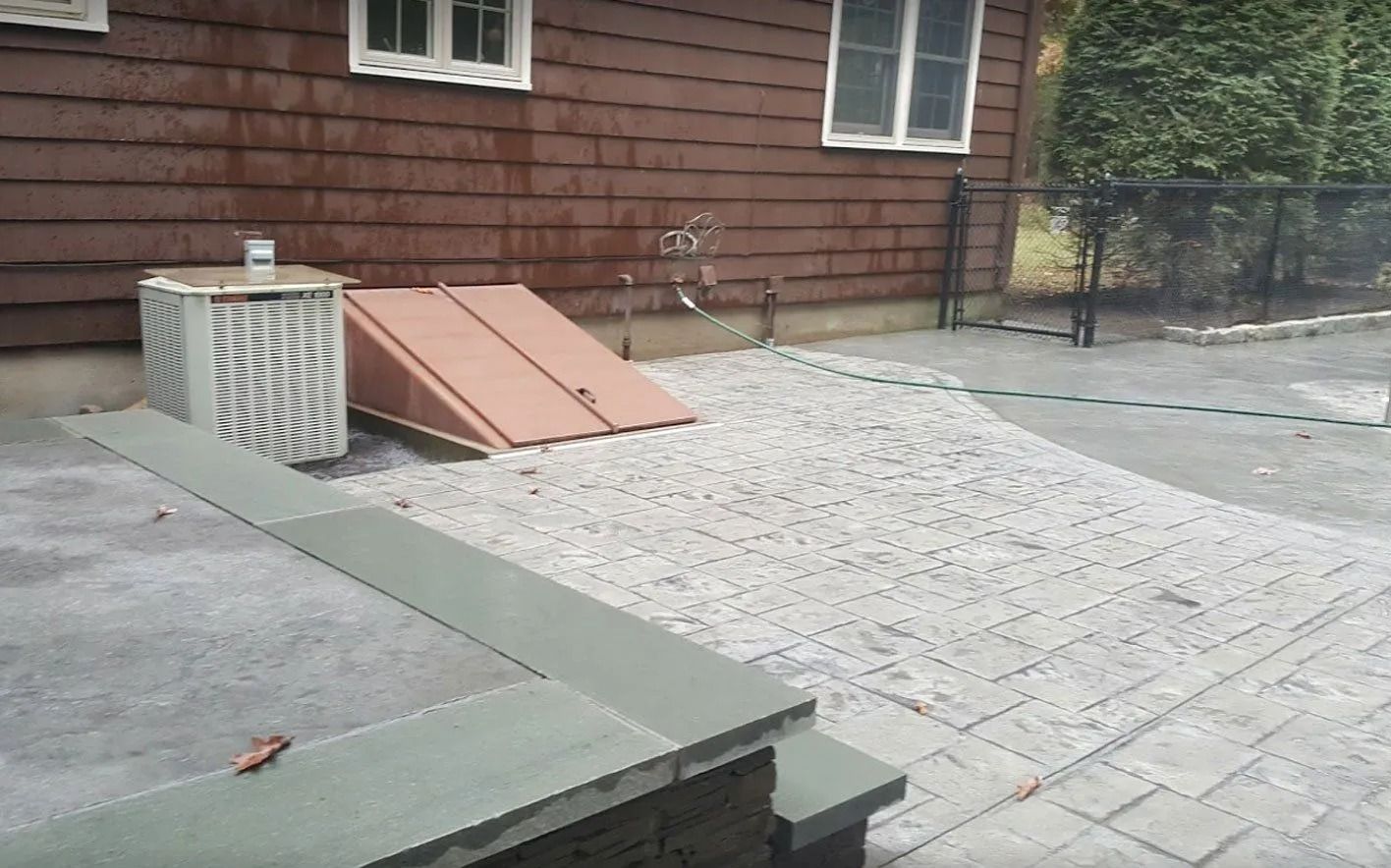 Brown house with patio, gravel, and steps. A cellar door and a utility box are in the frame.