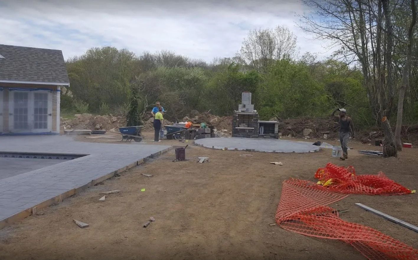 Construction site with workers, outdoor kitchen, and a pool area in progress.