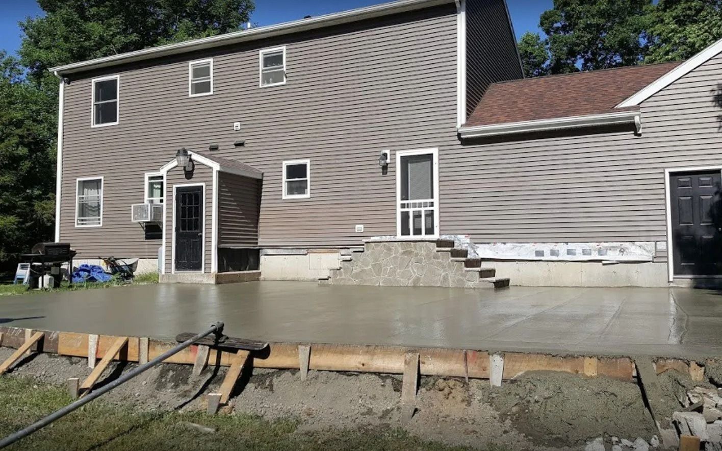 Back of a house with new concrete patio being poured, with wooden forms in foreground.