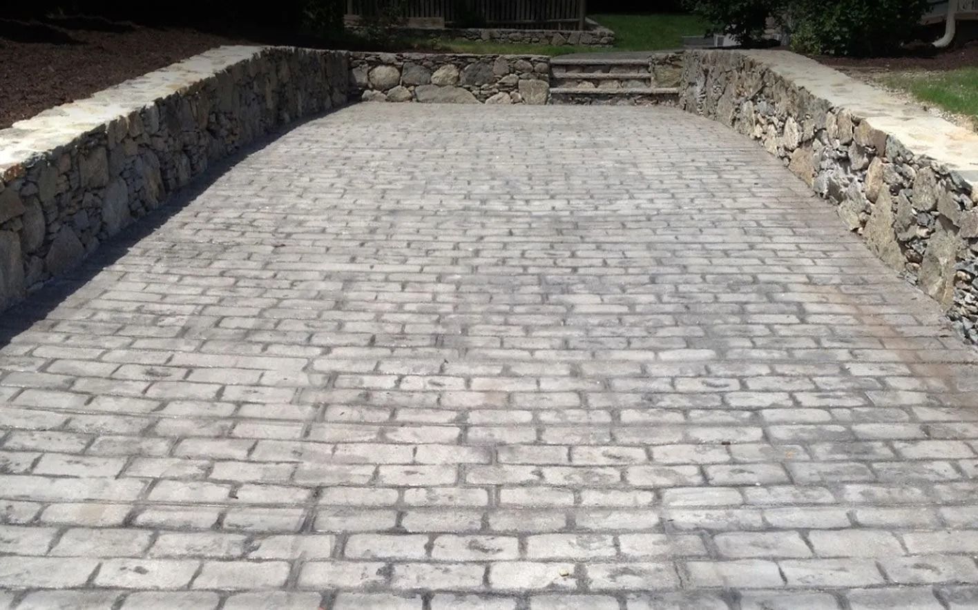 Stone brick paved driveway with stone retaining walls.