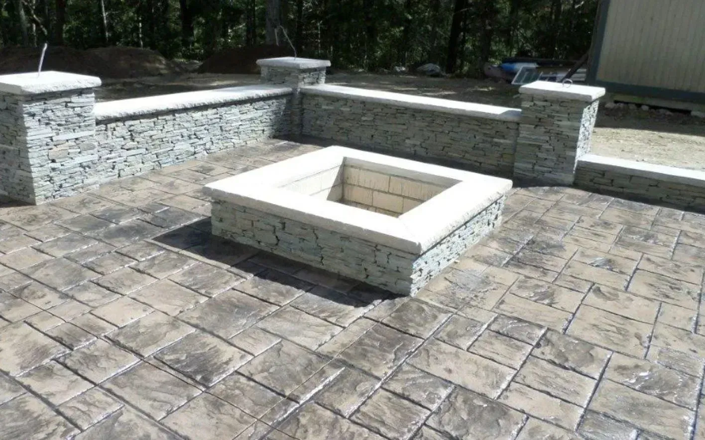 Stone fire pit and retaining walls on a stamped concrete patio, in an outdoor setting.