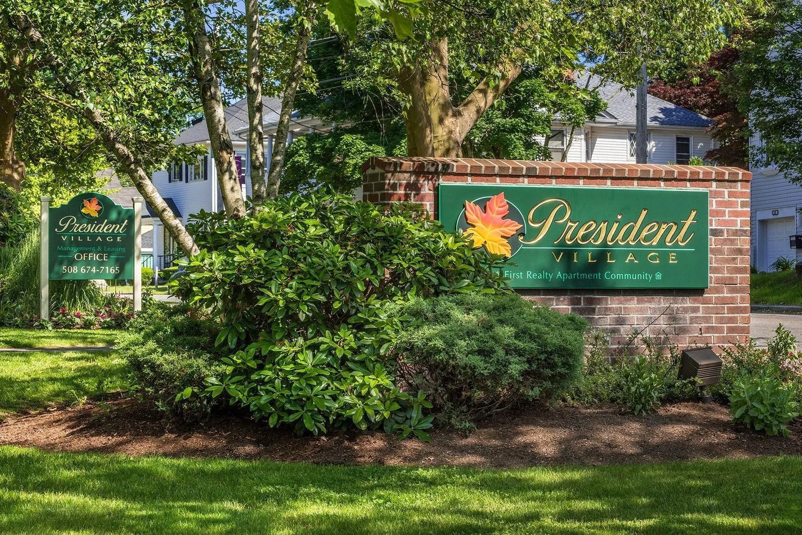 President Terrace sign with brick surround, surrounded by greenery and trees.