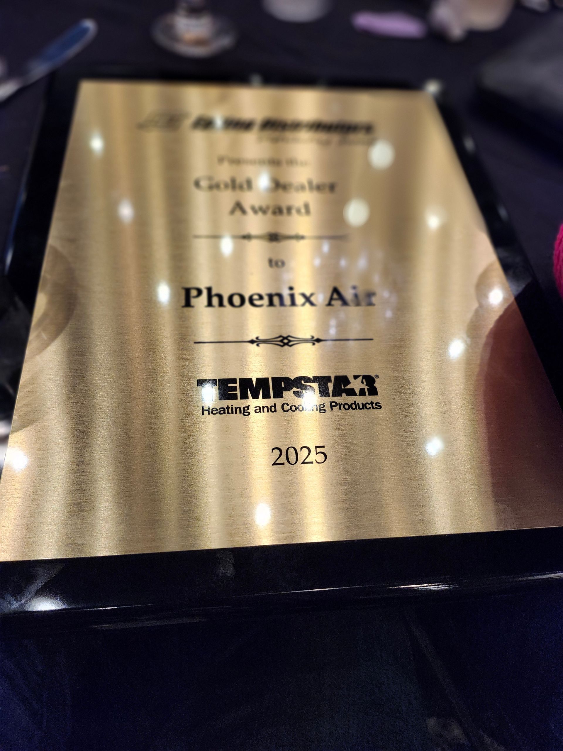 A 2023 Tempstar Gold Dealer Award plaque presented to Phoenix Air, featuring gold lettering on a metallic gold background.