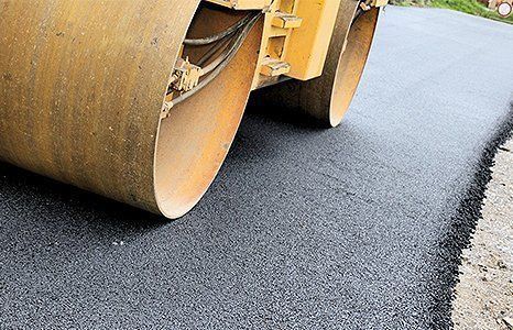 Road roller paving fresh black asphalt on a road surface