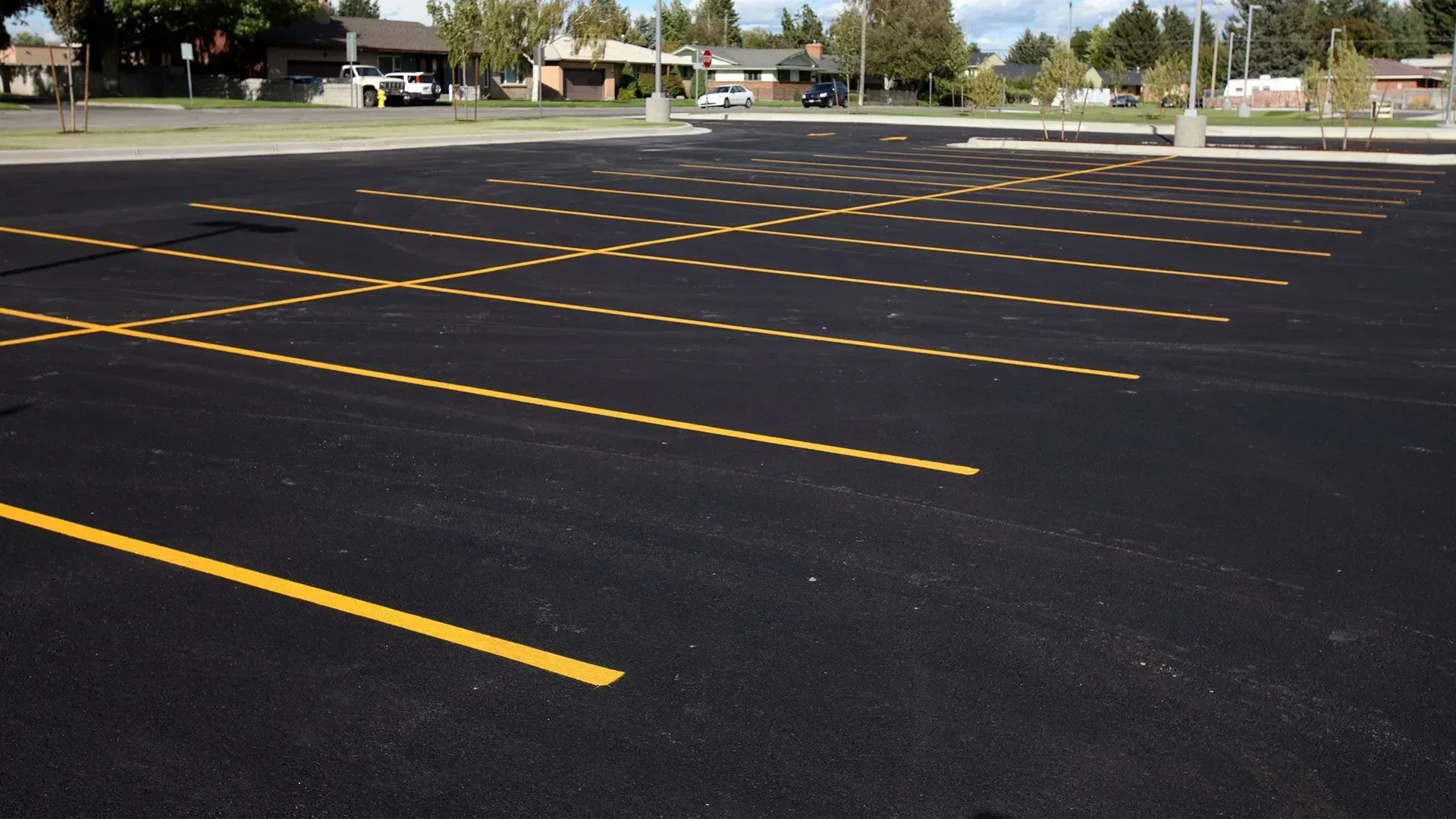 Empty parking lot with fresh yellow lines on dark asphalt under a clear sky