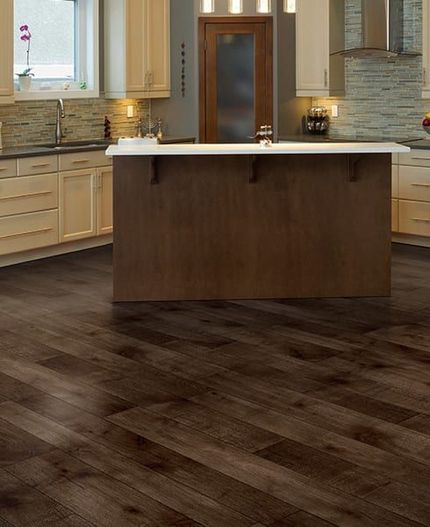 Spacious kitchen with dark wood flooring, white cabinets, and a large island with a white countertop.