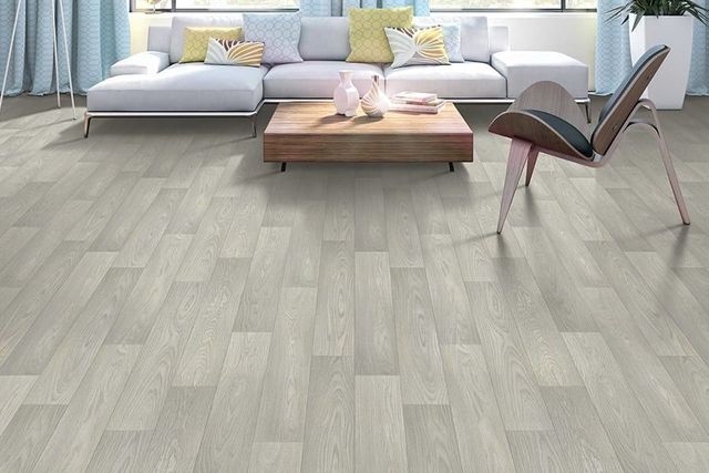 Modern living room with light gray wood flooring, a gray sofa, coffee table, and lounge chair