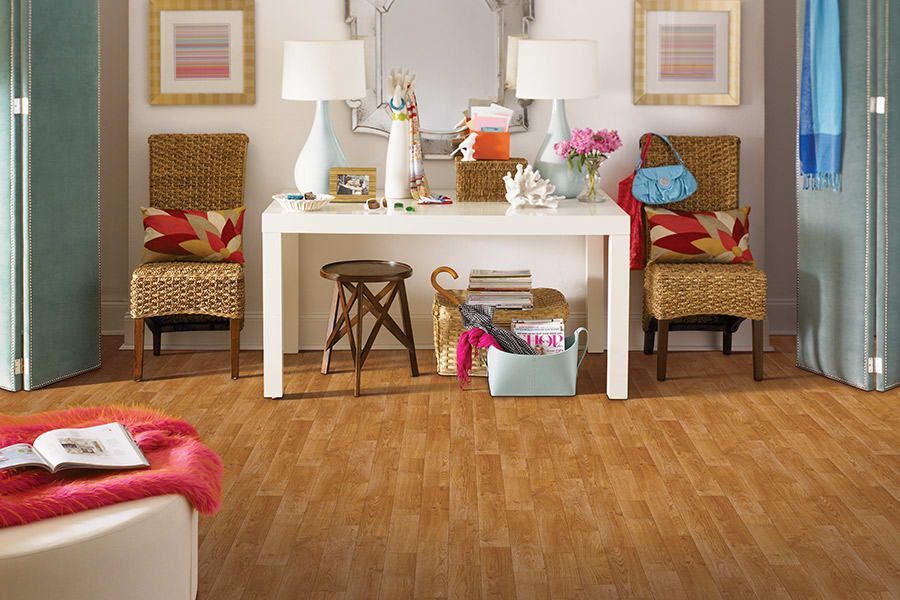 Cozy living room with white table, two chairs, lamps, flowers, and books on a wooden floor