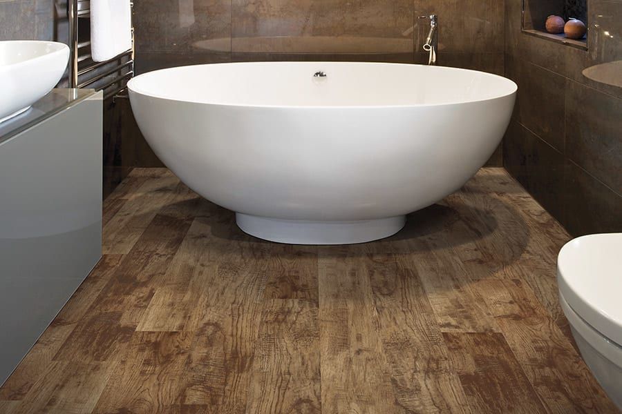 Modern bathroom with a freestanding white bathtub and wood-look tile floor