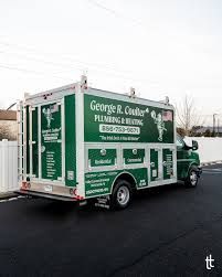 Green plumbing service truck with company branding parked on a street.