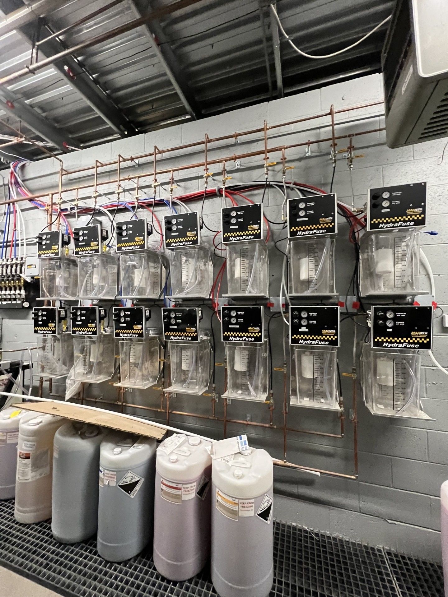 Display of hanging retail dispensers on a wall, with large containers on shelves below.