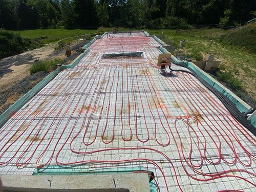 Hydronic floor heating tubing laid over insulated concrete slab at a construction site