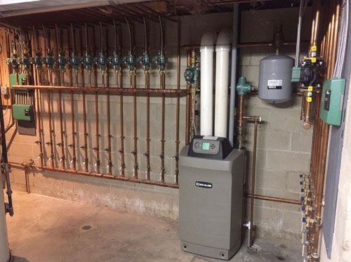Mechanical room with pipes, valves, and two gray utility units along a wall