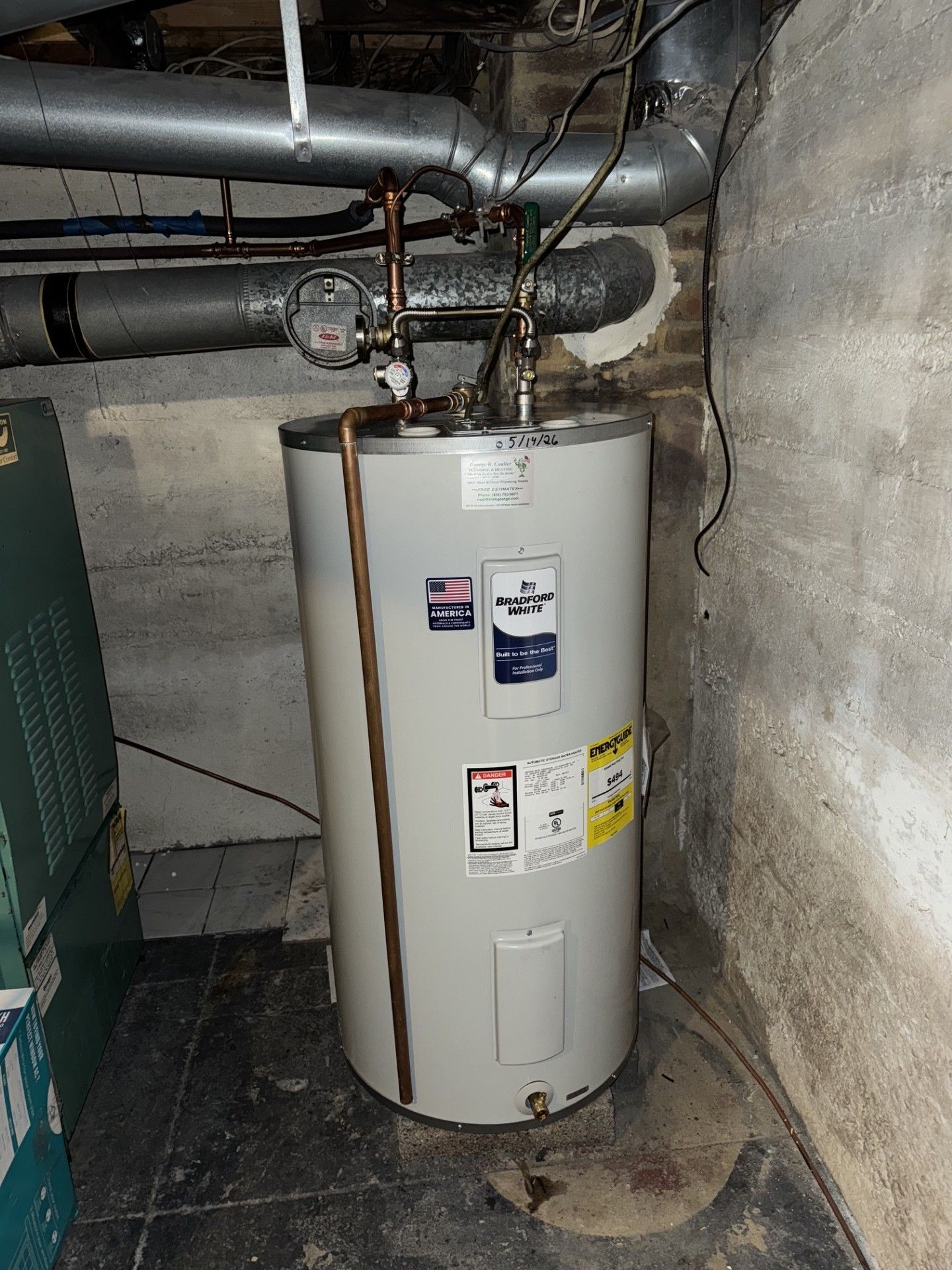 White water heater in a basement utility room with exposed pipes and a concrete floor.