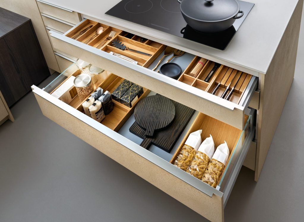 Open kitchen drawer with organized wooden spice and utensil compartments under a stovetop.