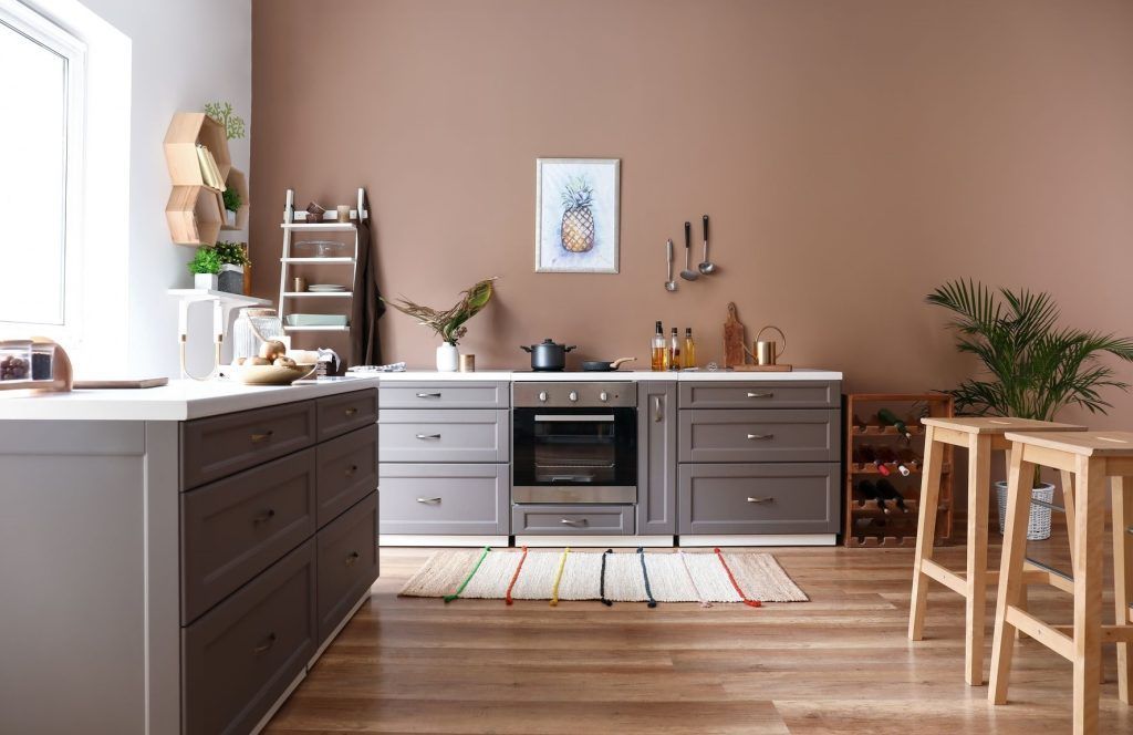 Modern kitchen with gray cabinets, wooden island, and stool seating beside a window.
