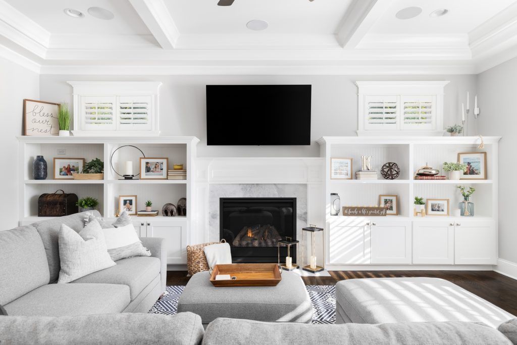 Bright white living room with sectional sofa, fireplace, built-in shelves, and wall-mounted TV