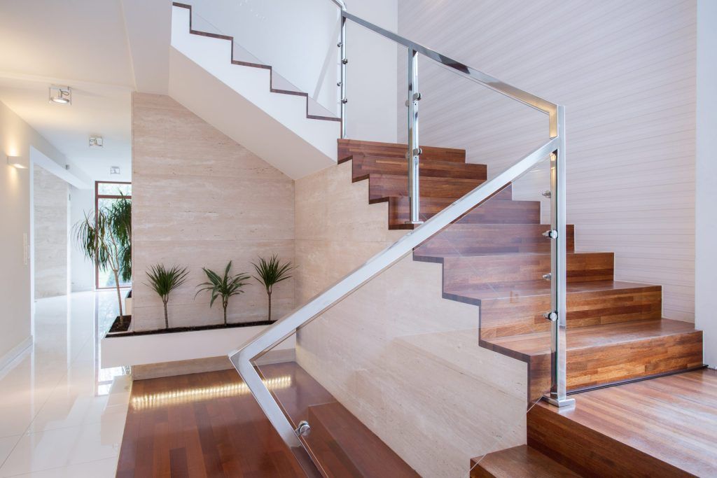 Modern indoor staircase with wooden steps, glass railing, and white walls in a bright hallway