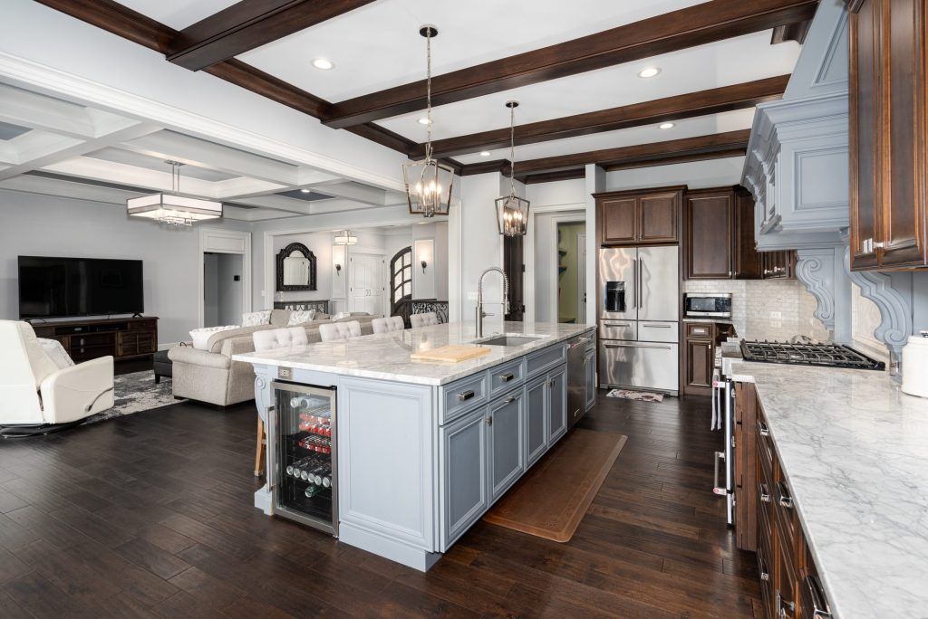 Bright open kitchen with gray island, white countertops, wood beams, and adjoining living area