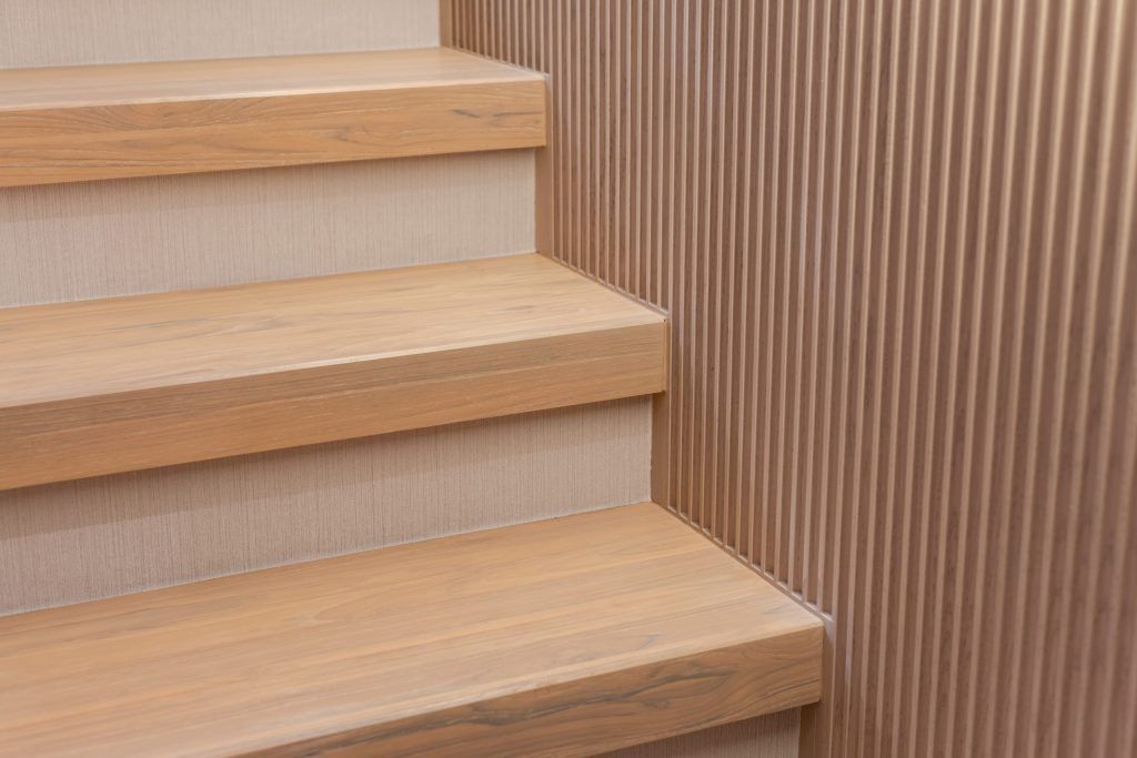 Close-up of light wood stairs beside a vertical slatted wood wall