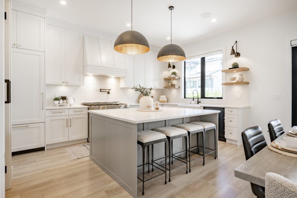 Bright modern kitchen with white cabinets, large island, pendant lights, and bar stools
