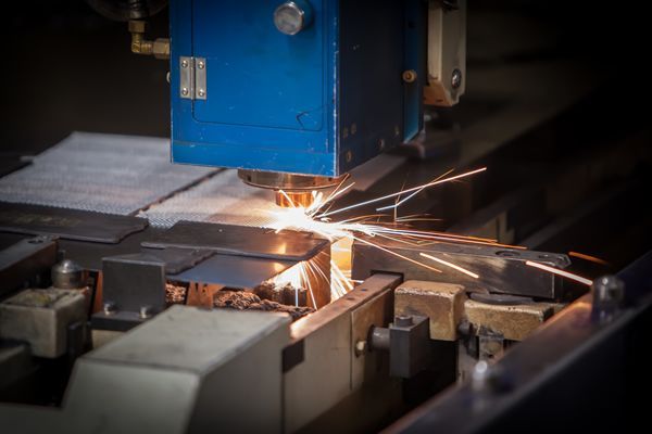 A machine is cutting a piece of metal with sparks coming out of it.