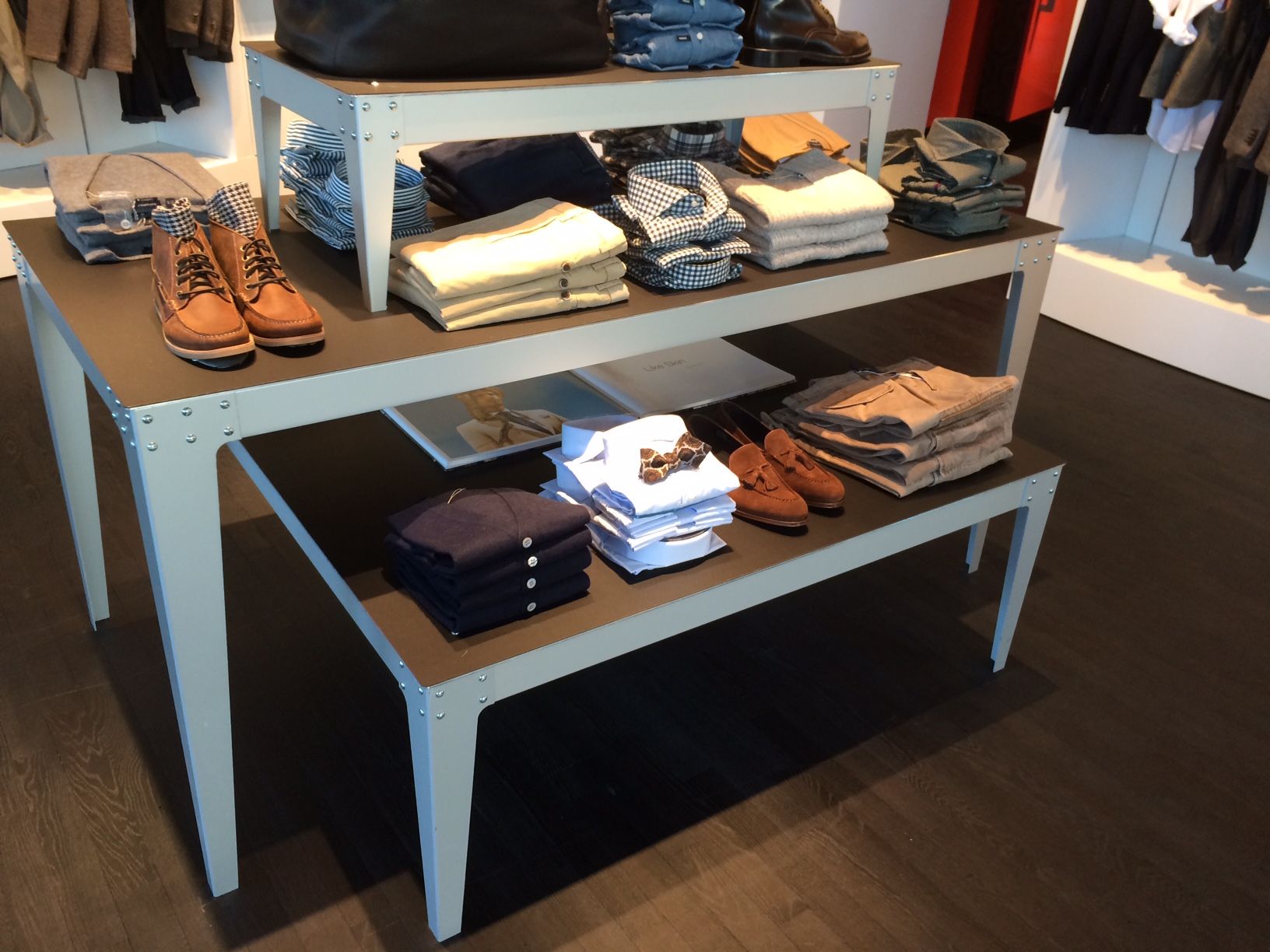 A table with shirts and shoes on it in a store.