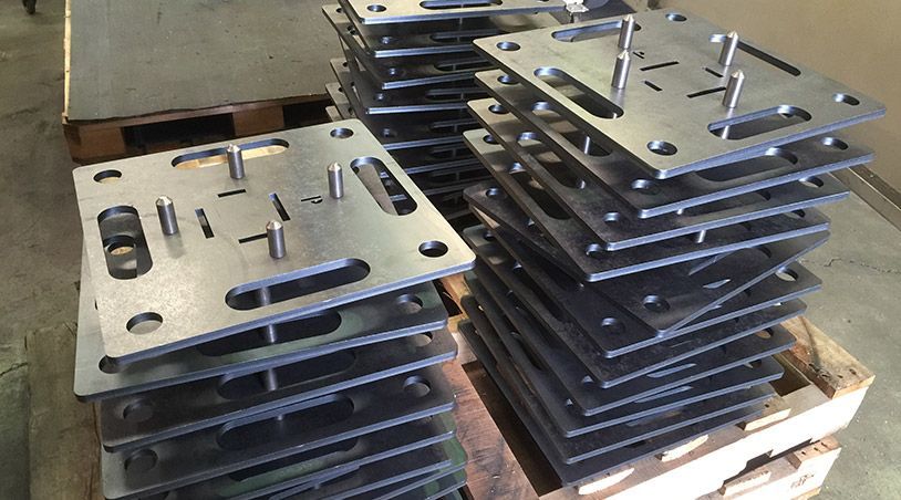 A pile of metal plates stacked on top of each other on a wooden pallet.
