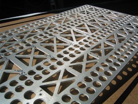 A piece of metal with holes in it is laying on a table.