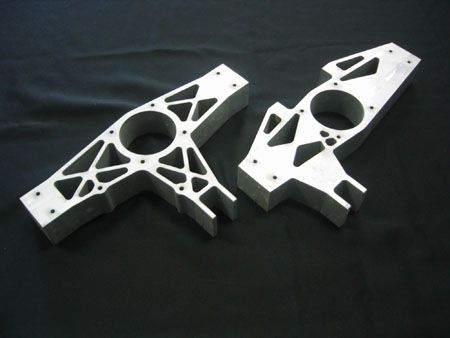 Two pieces of metal with holes in them on a black surface.