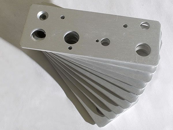 A stack of metal plates with holes in them on a white surface.